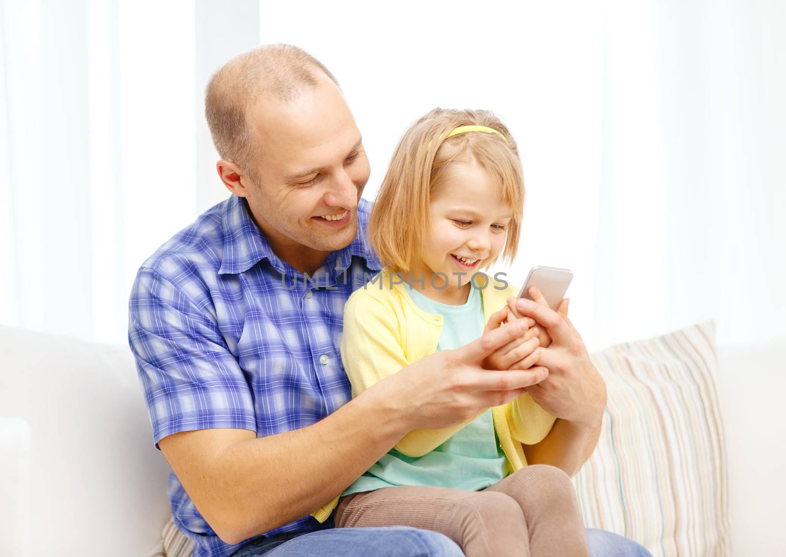 family, children, parenthood, technology and internet concept - happy father and daughter with smartphone at home