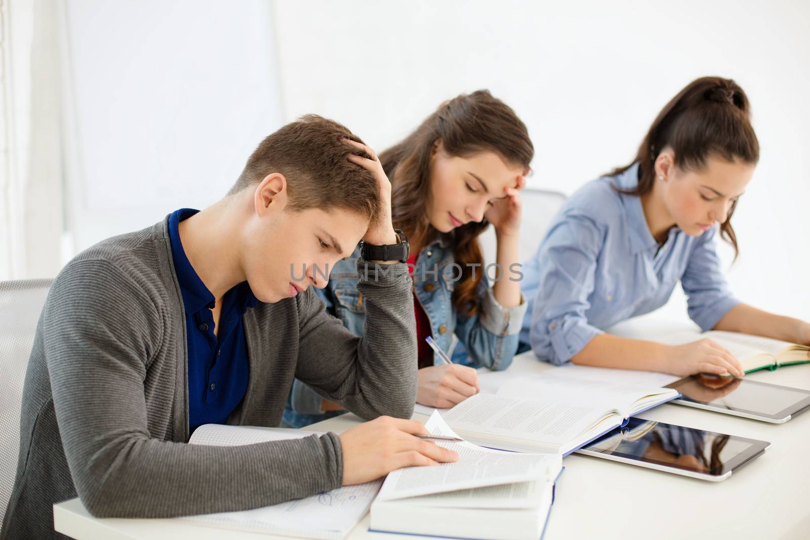 school and education concept - group of tired students with notebooks at school