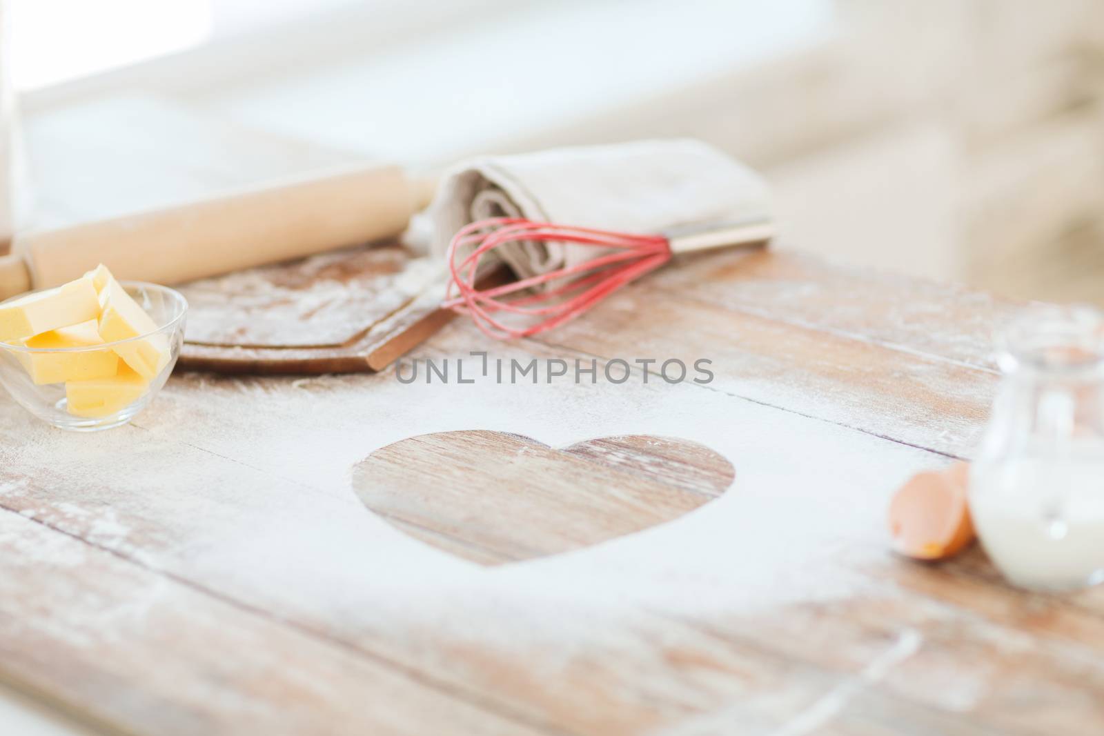 cooking and love concept - close up of heart of flour on wooden table at home