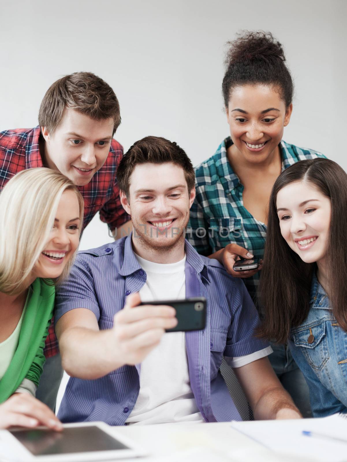 students looking into smartphone at school by dolgachov