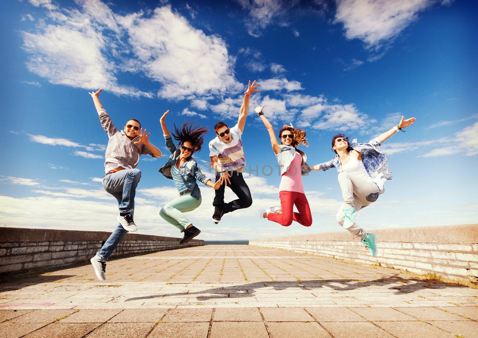 summer, sport, dancing and teenage lifestyle concept - group of teenagers jumping