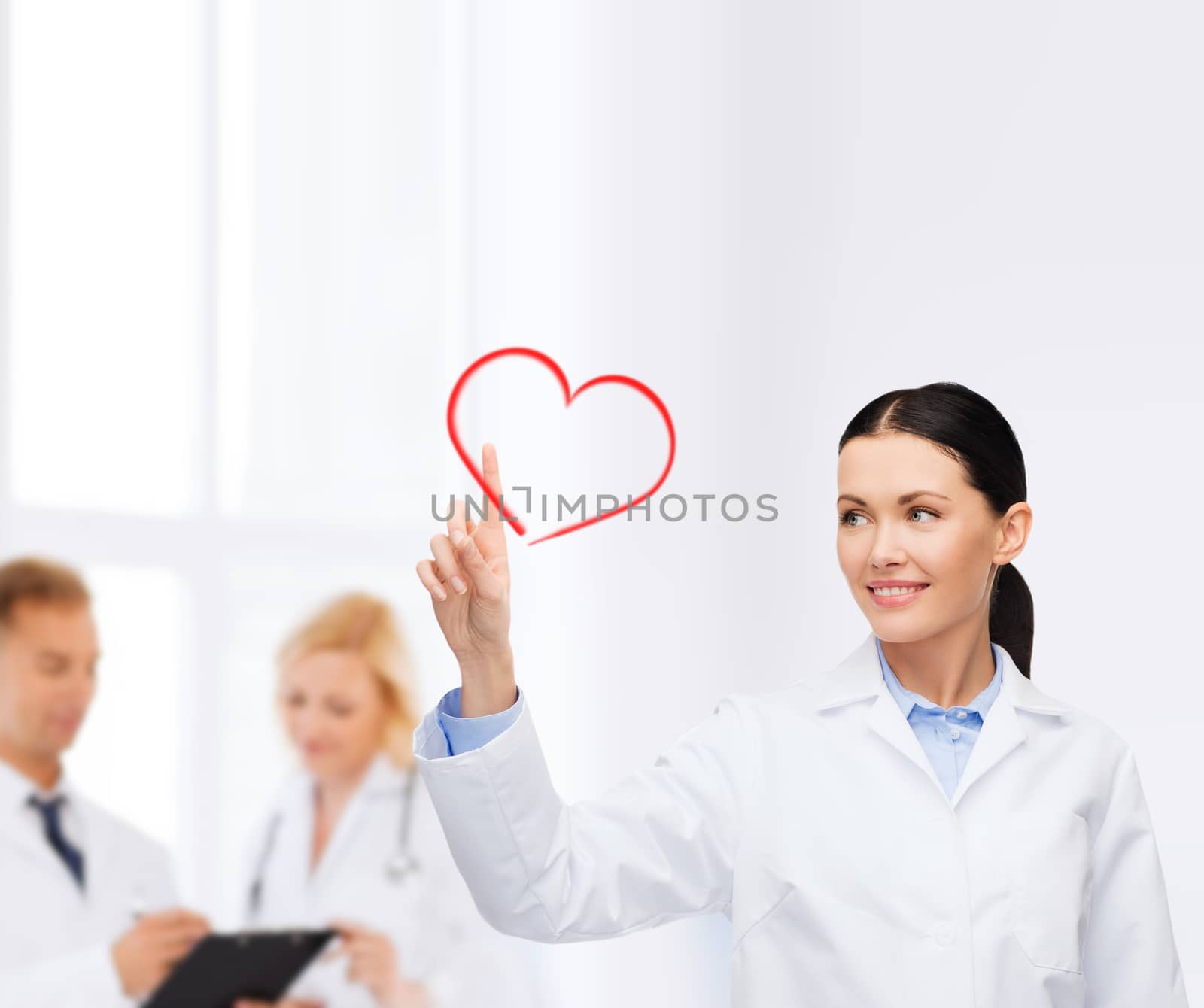 smiling female doctor pointing to heart by dolgachov