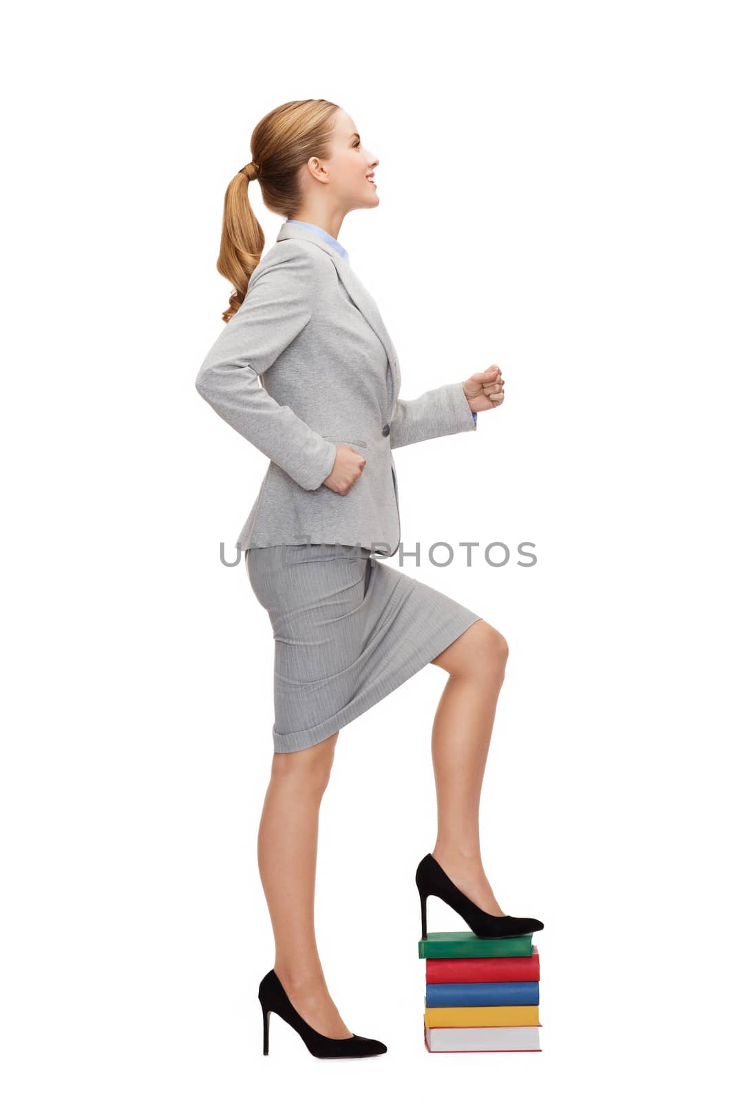 smiling businesswoman stepping on pile of books by dolgachov