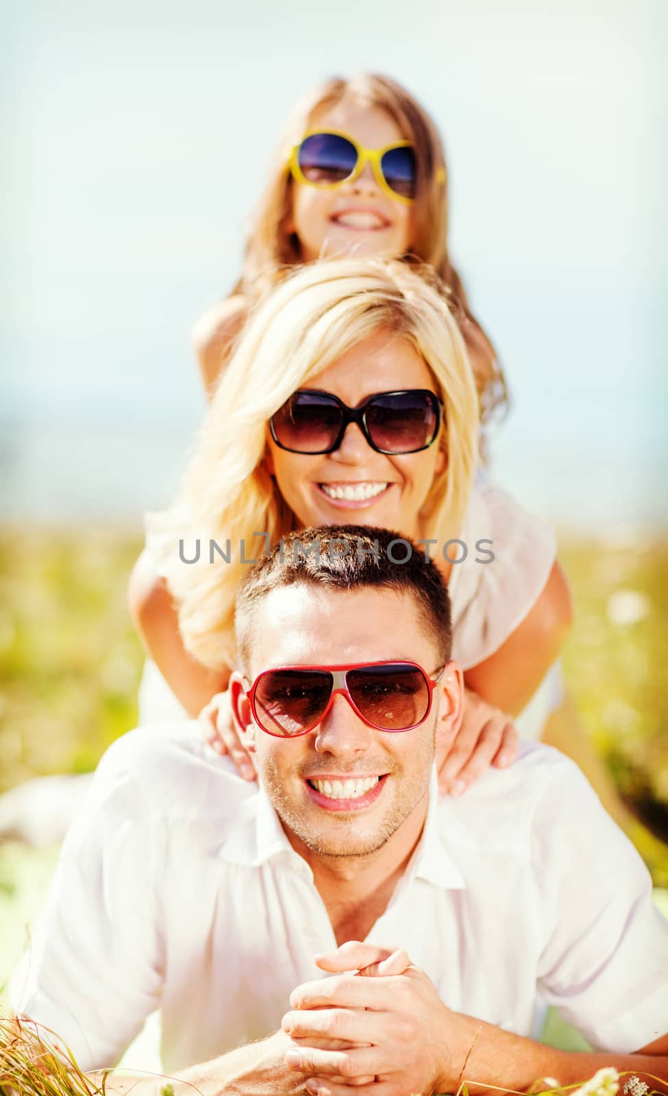 summer holidays, children and people concept - happy family with blue sky and green grass