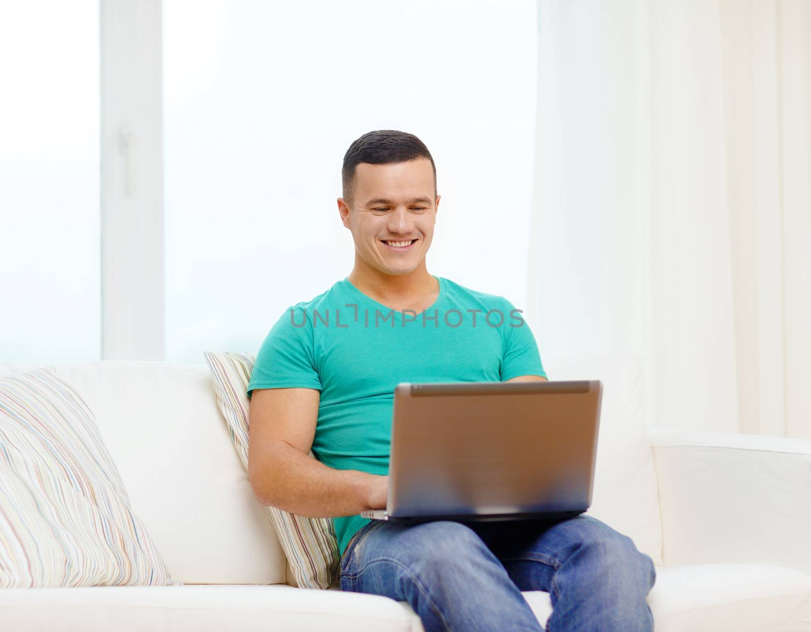 smiling man working with laptop at home by dolgachov