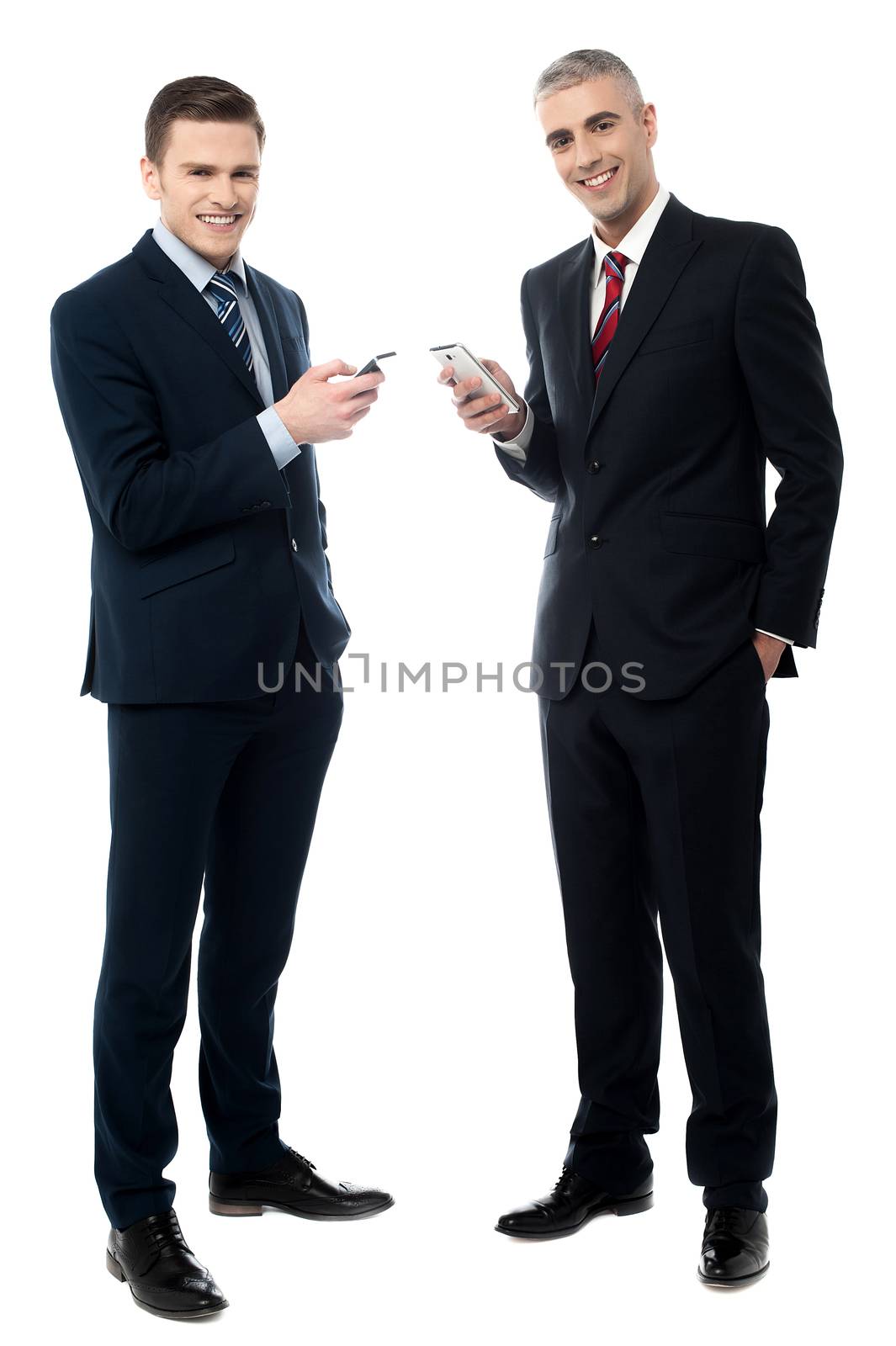 Smiling businessmen using cellphone by stockyimages