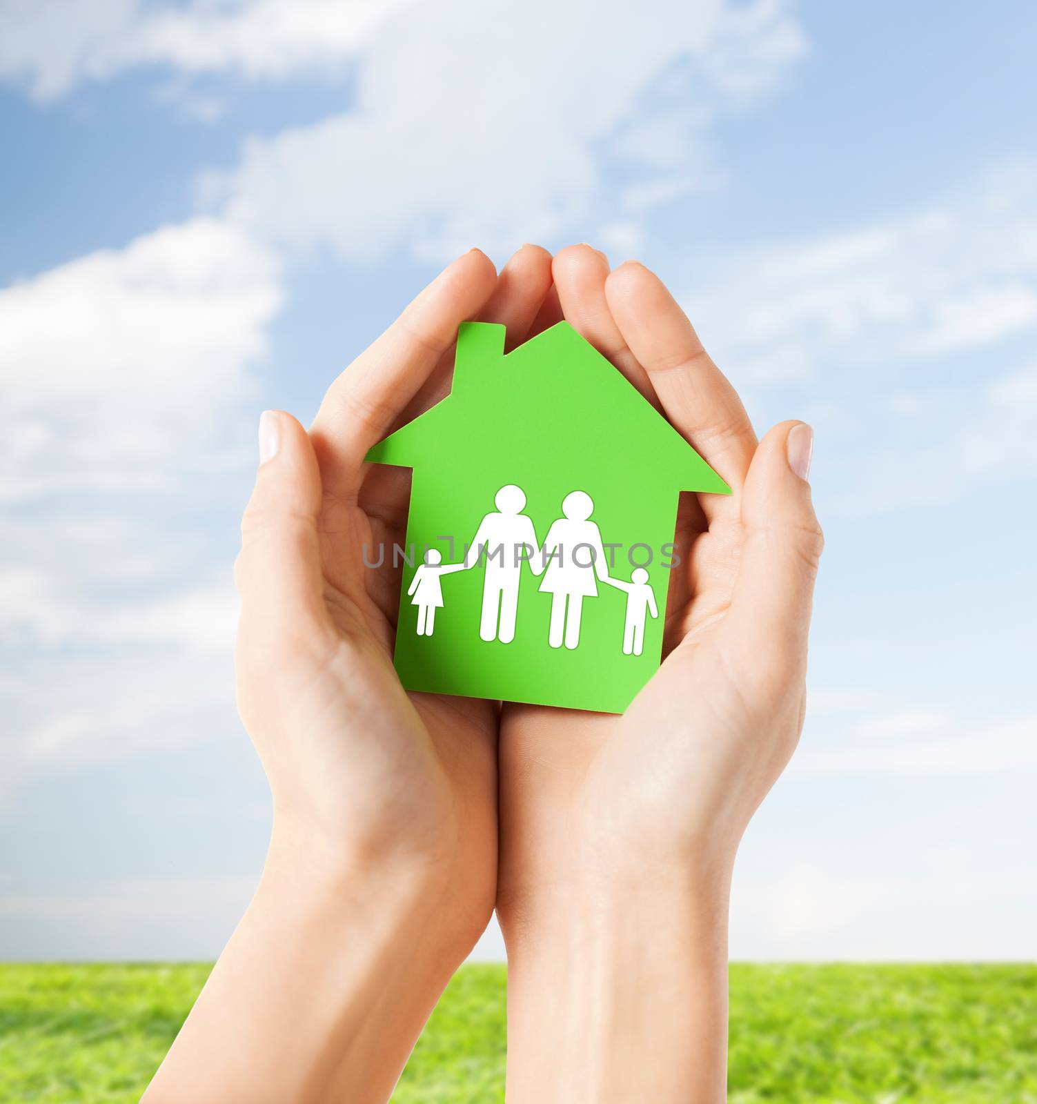 real estate and family home concept - closeup picture of female hands holding green paper house with family