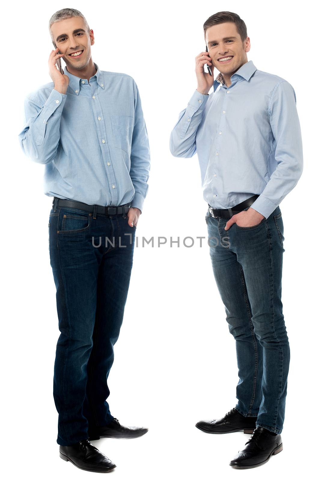 Two young men talking through mobile phone by stockyimages