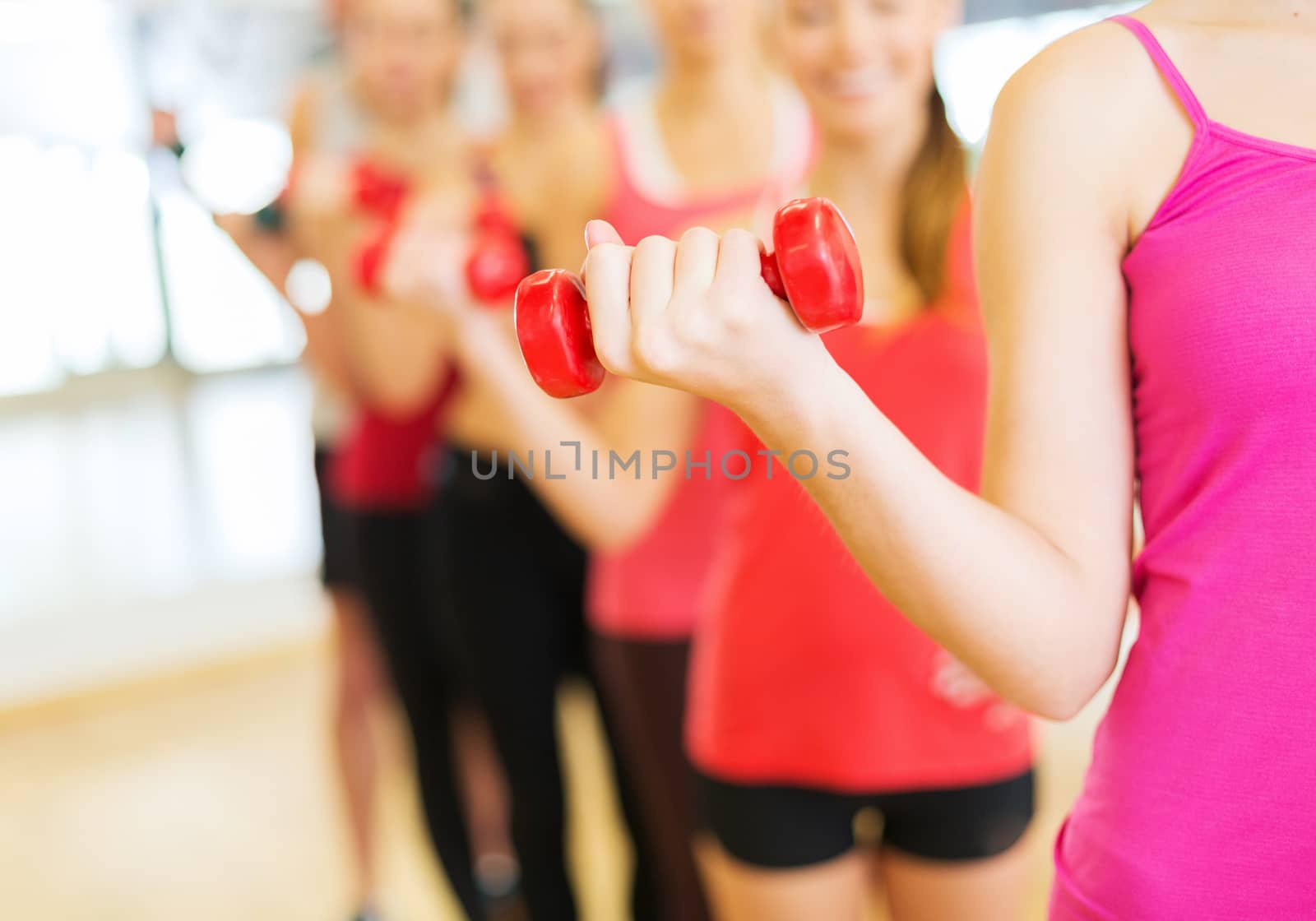 fitness, sport, training, gym and lifestyle concept - group of people working out with dumbbells in the gym