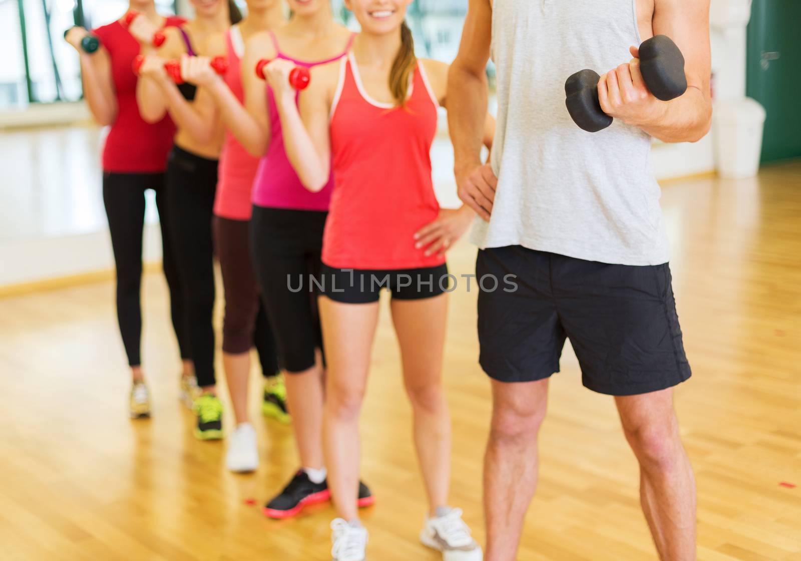 fitness, sport, training, gym and lifestyle concept - group of people working out with dumbbells in the gym