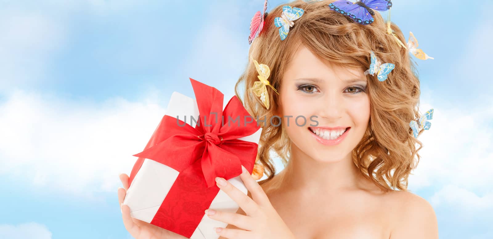 health, holidays and beauty concept - happy teenage girl with butterflies in hair showing gift box