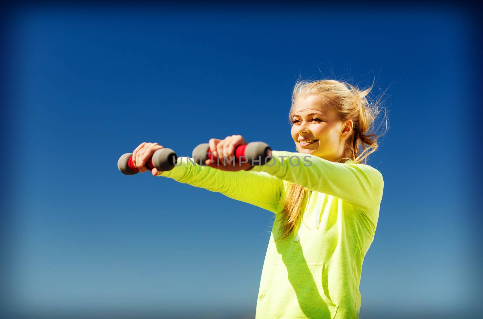 sporty woman with light dumbbells outdoors by dolgachov