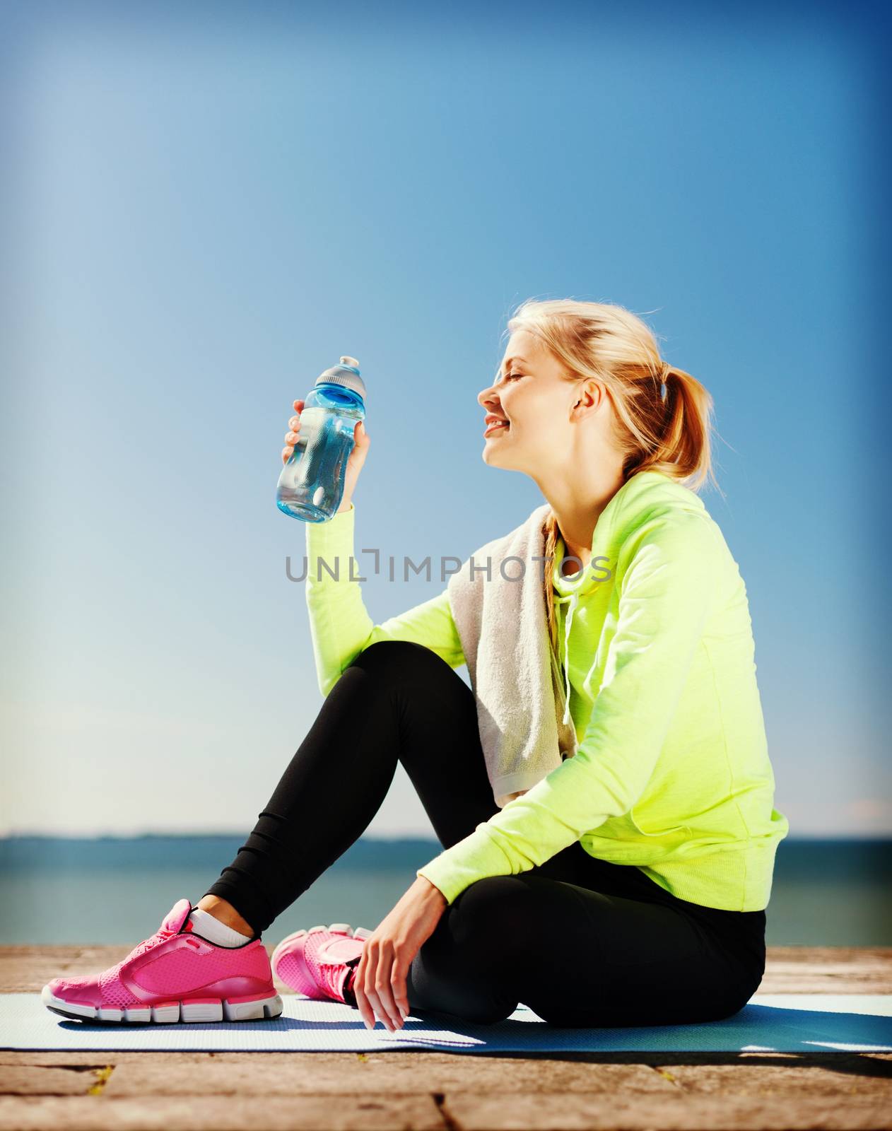 woman drinking water after doing sports outdoors by dolgachov