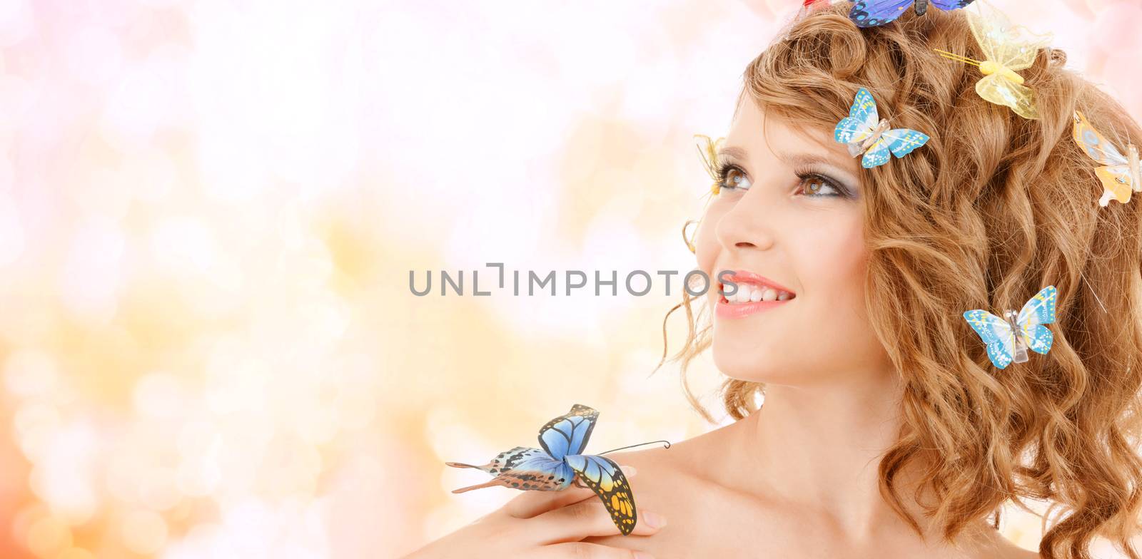 health and beauty concept - happy teenage girl with butterflies in hair and one sitting on her hand