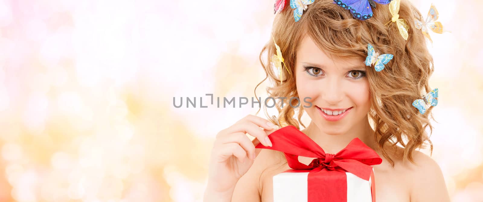 health, holidays and beauty concept - happy teenage girl with butterflies in hair opening gift box