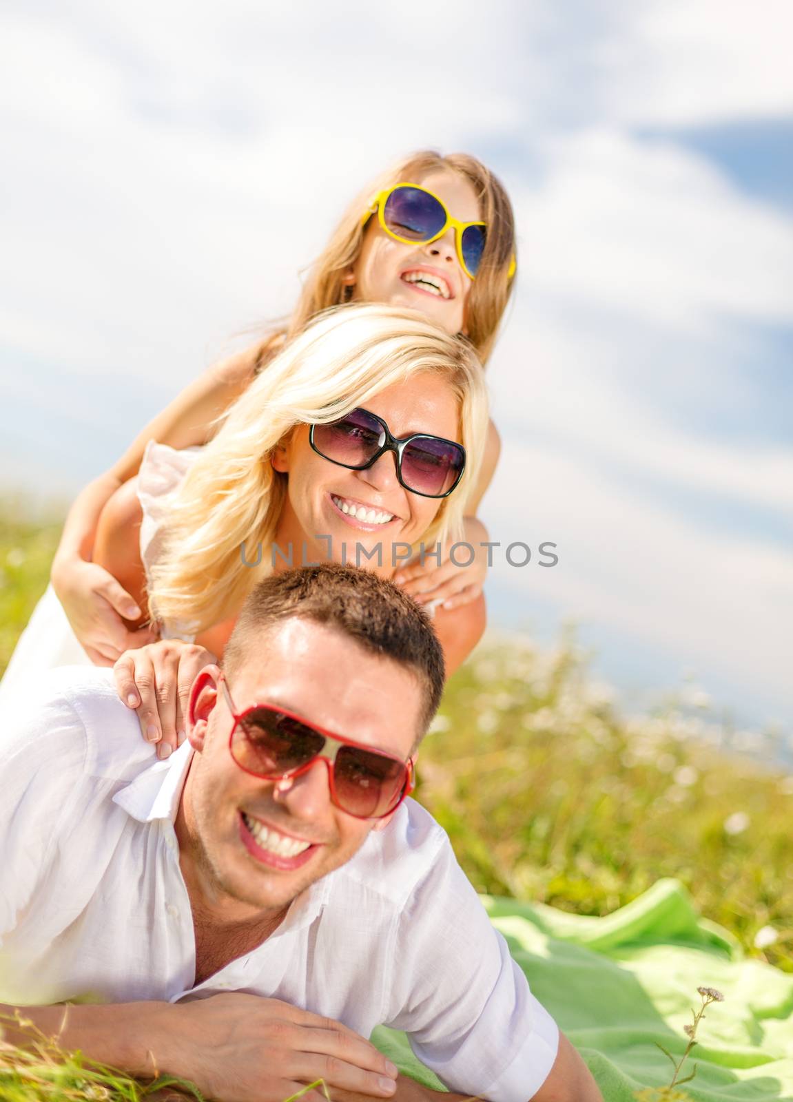smiling family in sunglasses lying on blanket by dolgachov