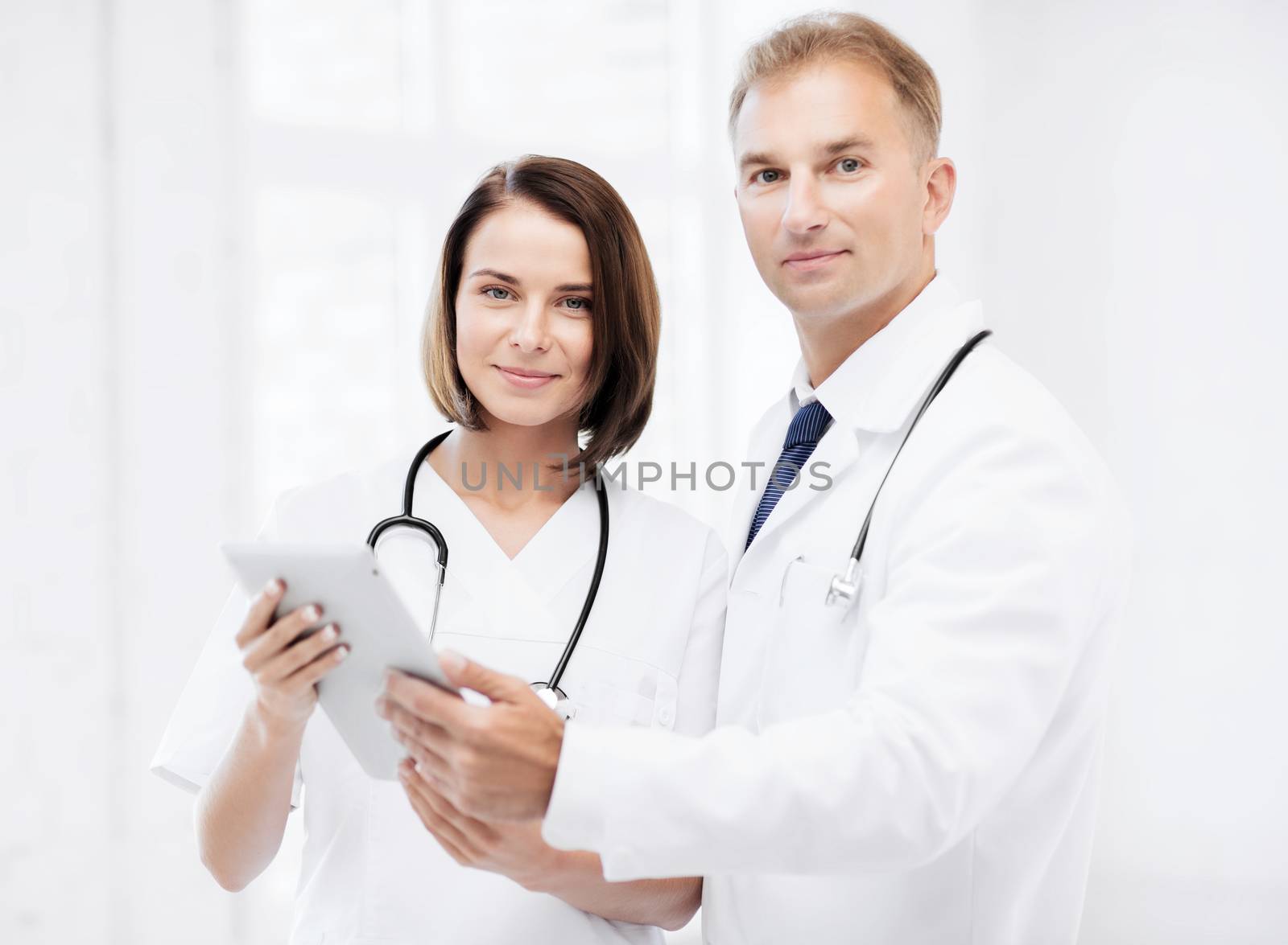 two doctors looking at tablet pc by dolgachov