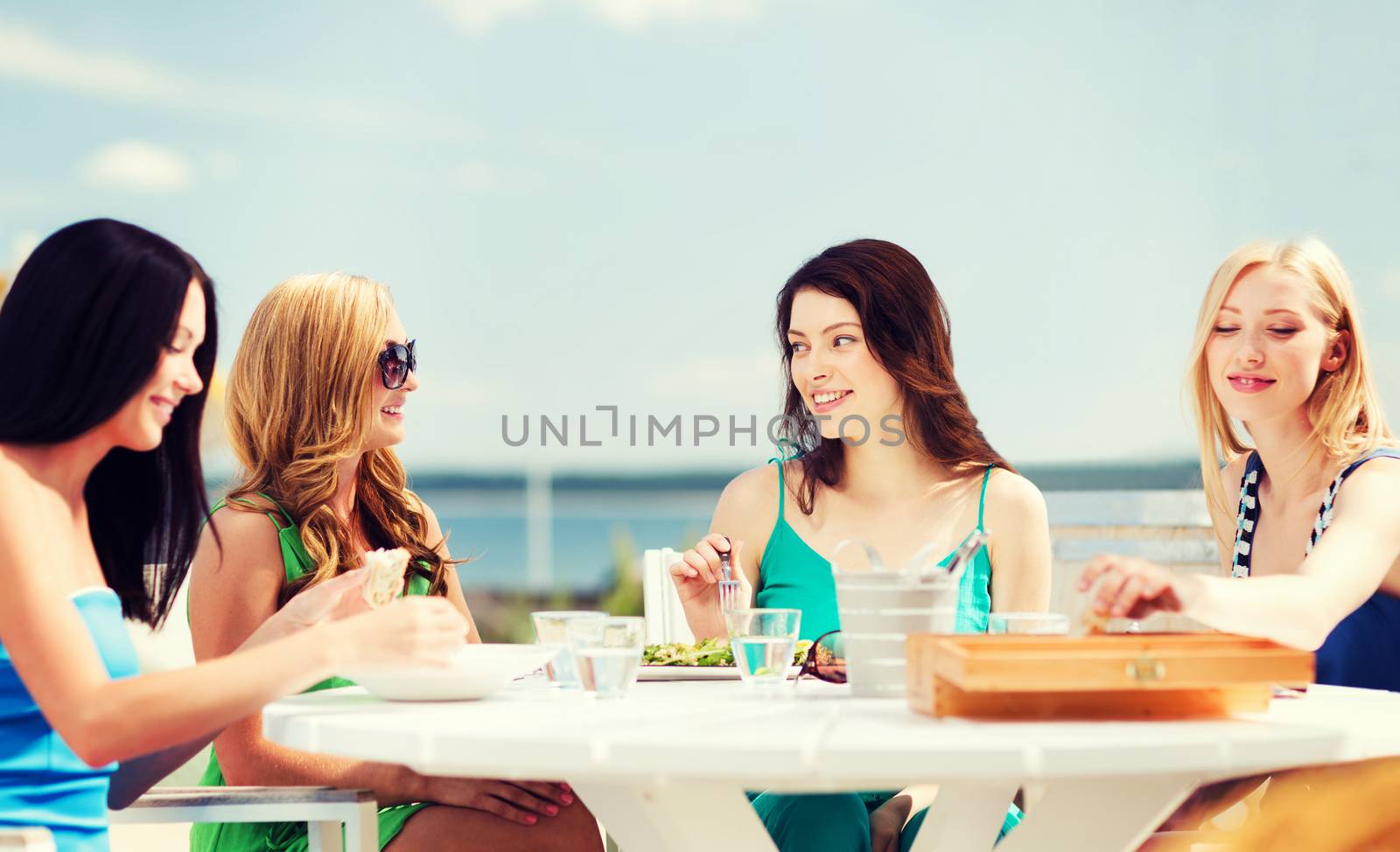 summer holidays and vacation - girls in cafe on the beach