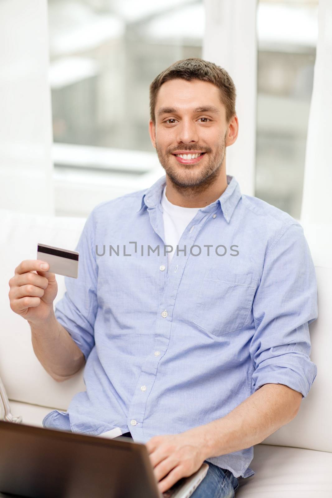technology, home and lifestyle concept - smiling man working with laptop and credit card at home