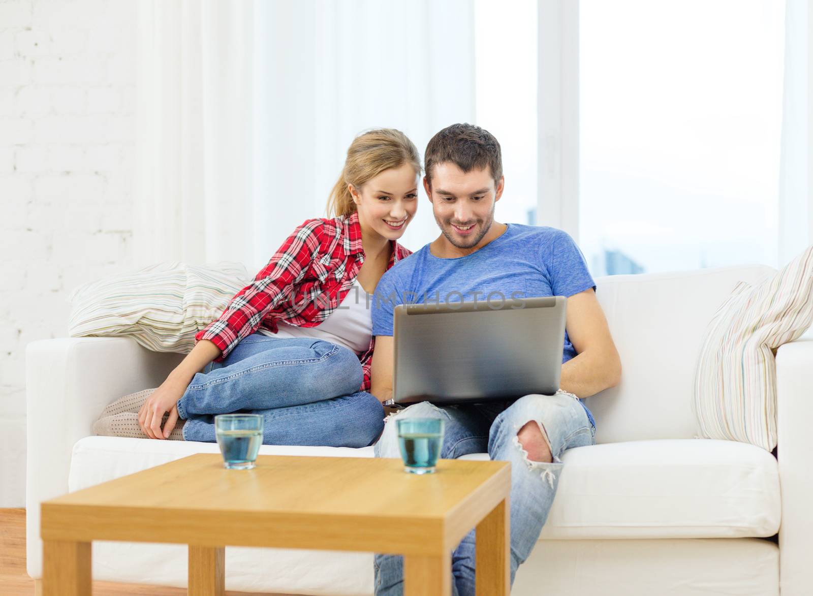 home, technology and relationships concept - smiling couple with laptop computer at home