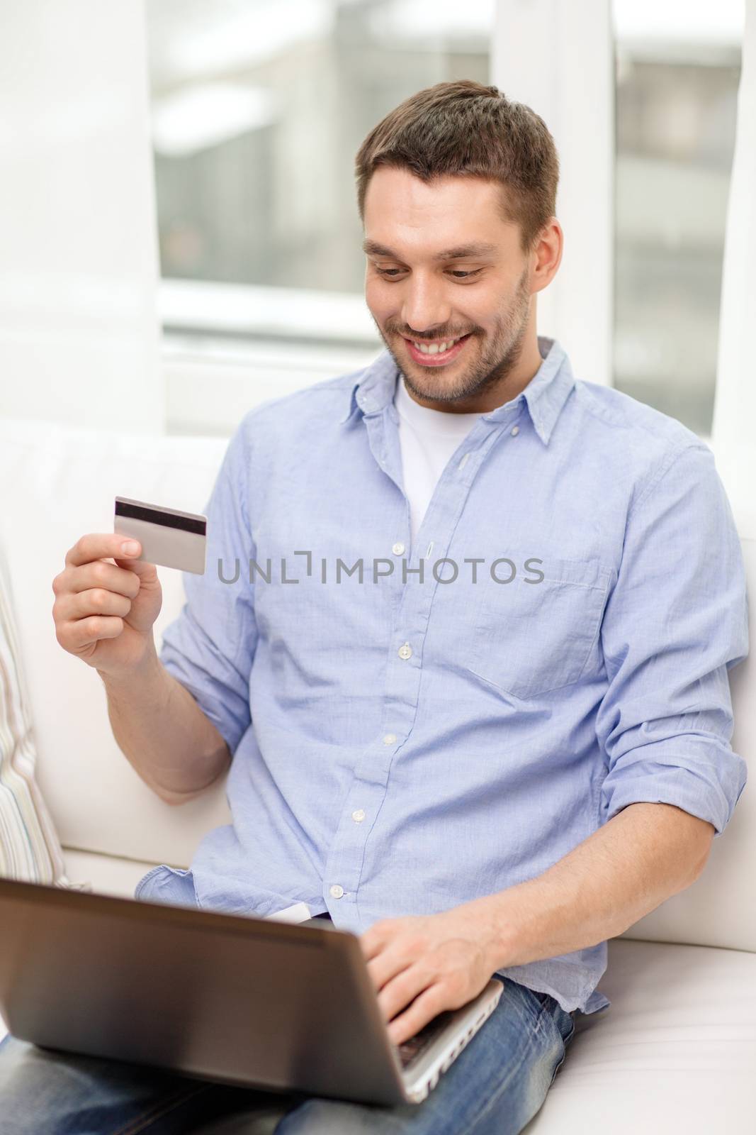 smiling man working with laptop and credit card by dolgachov