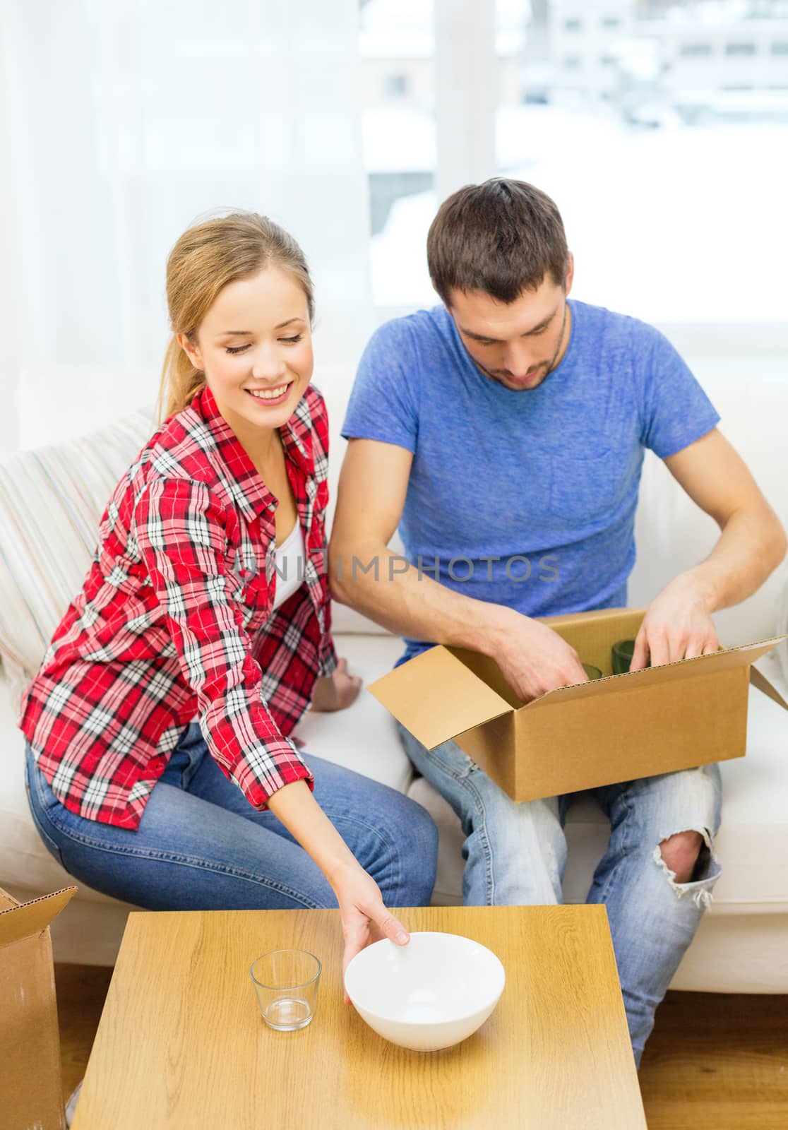 repair, building and home concept - smiling couple unpacking kitchenware