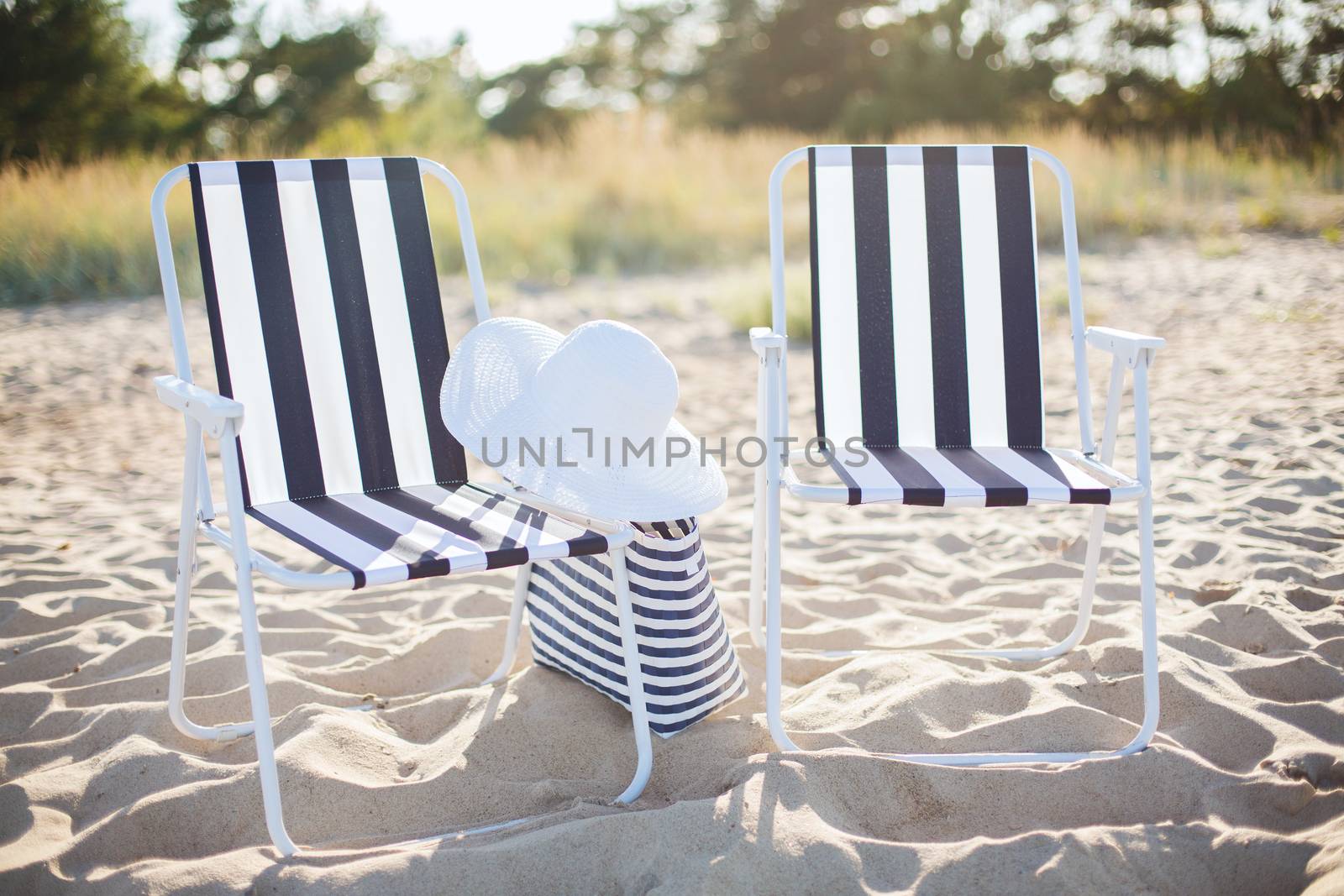 two beach lounges with beach bag and white hat by dolgachov