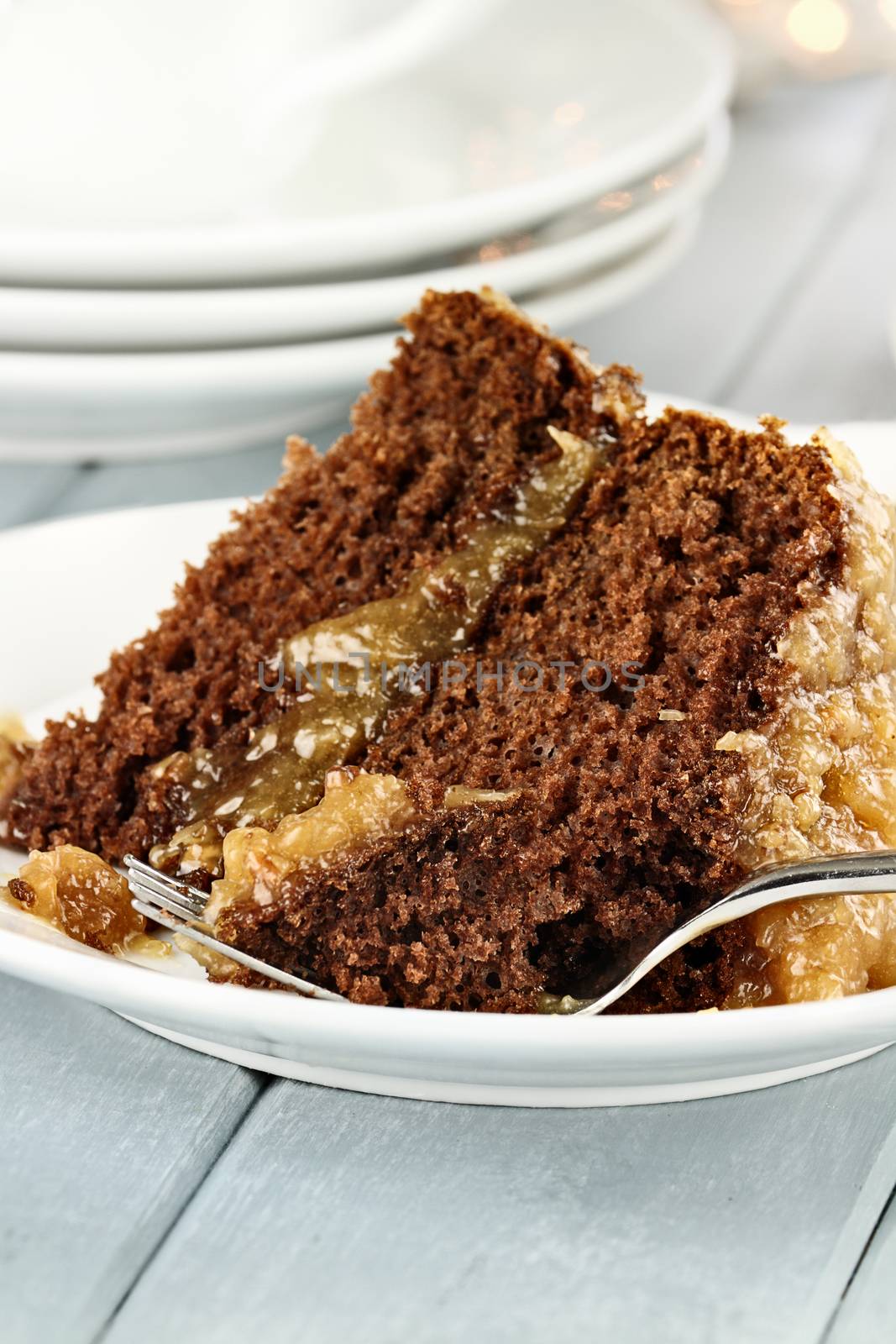 A slice of German chocolate cake on a plate. Shallow depth of field with selective focus on bite on the fork.