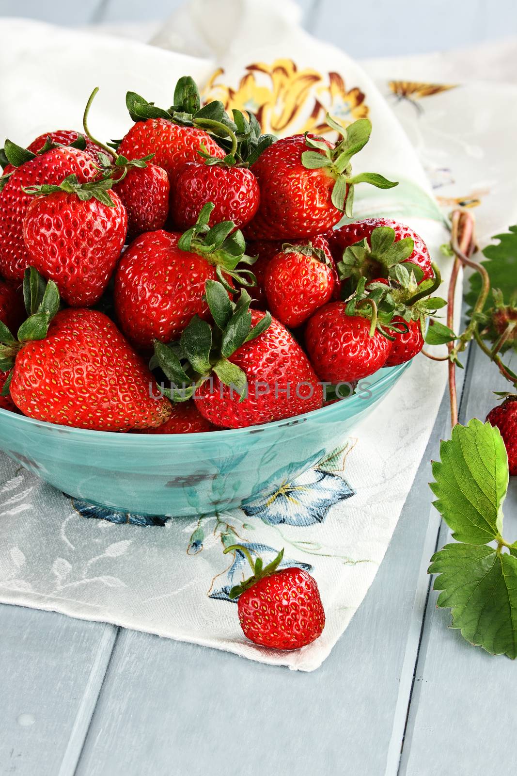 Fresh ripe strawberries in a beautiful blue bowl with selective focus and extreme shallow depth of field.