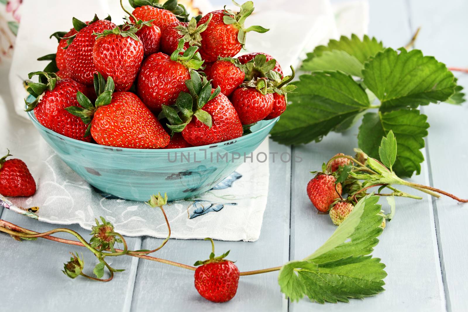 Fresh ripe strawberries in a beautiful blue bowl with selective focus and extreme shallow depth of field.