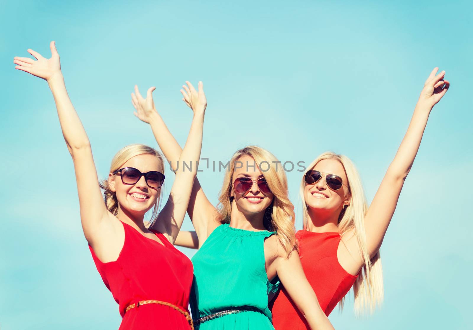 holidays and tourism, friends, hen party, blonde girls concept - three beautiful women waving hands over sky background