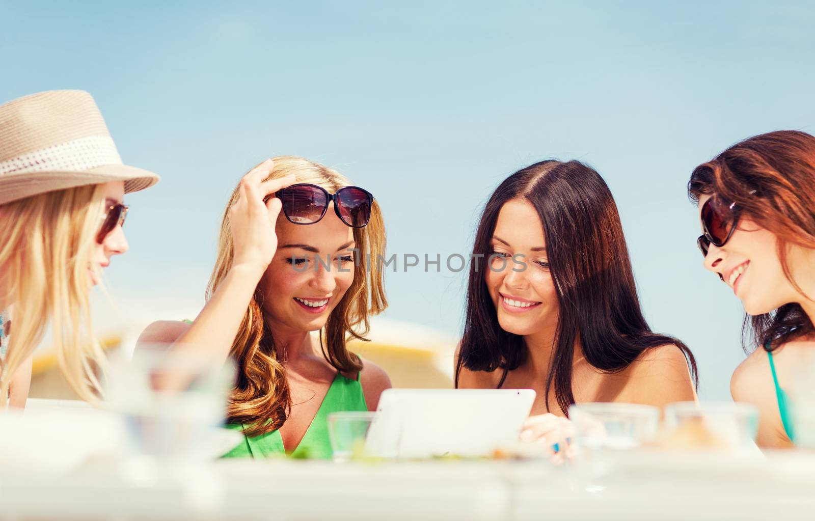 summer holidays, vacation, internet and technology - girls looking at tablet pc in cafe