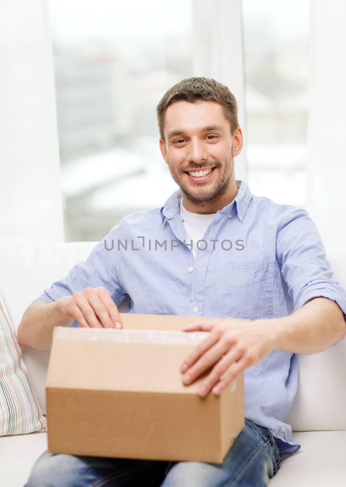 post, home and lifestyle concept - smiling man with cardboard boxes at home