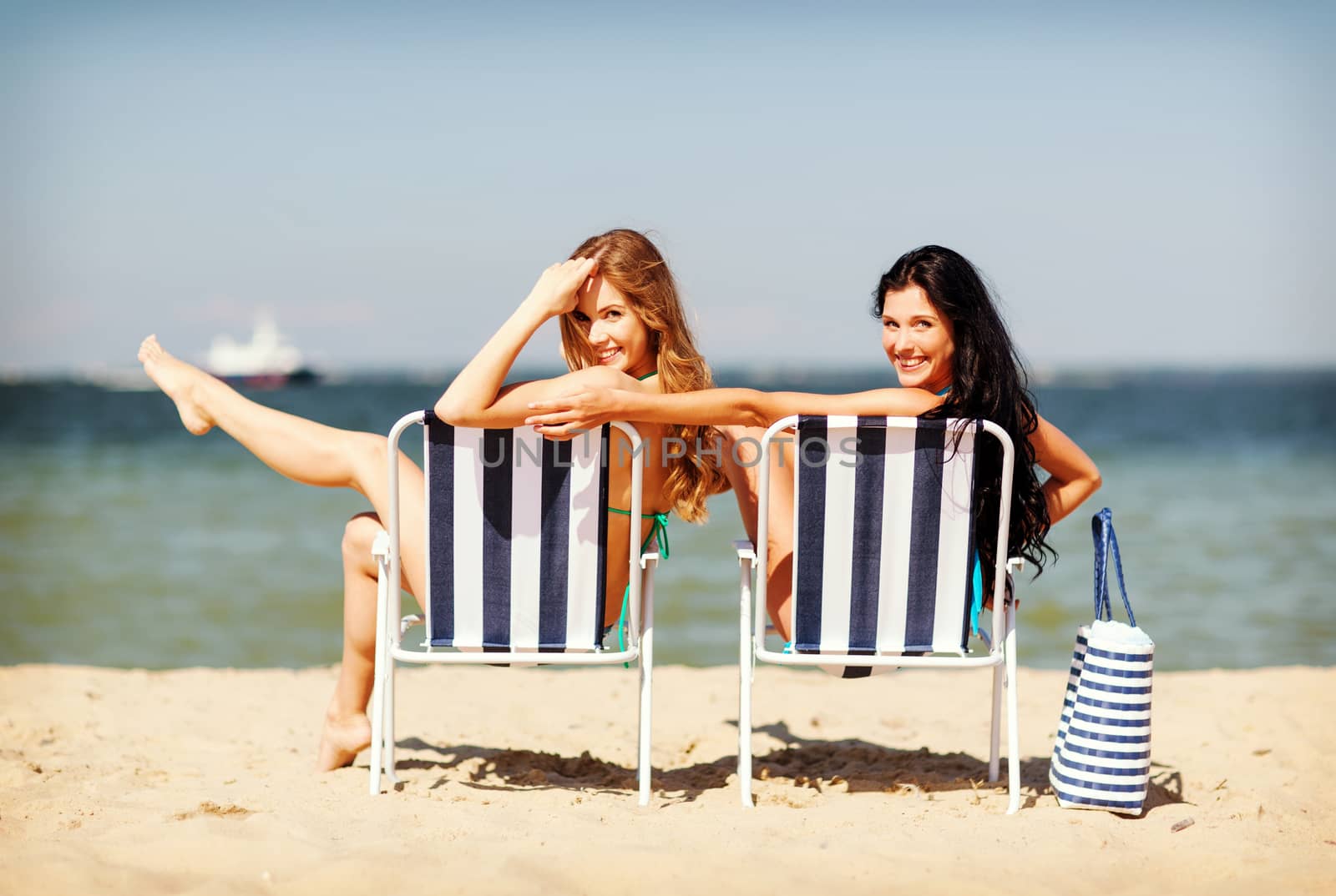 summer holidays and vacation - girls in bikinis sunbathing on the beach chairs