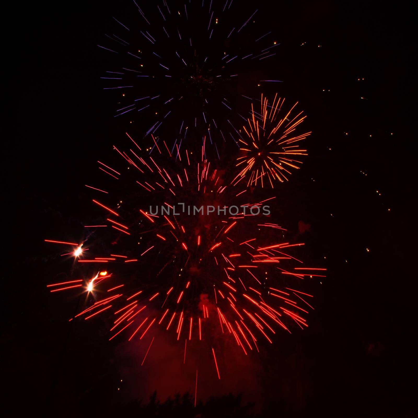 Red, yellow and blue fireworks exploding in the black sky