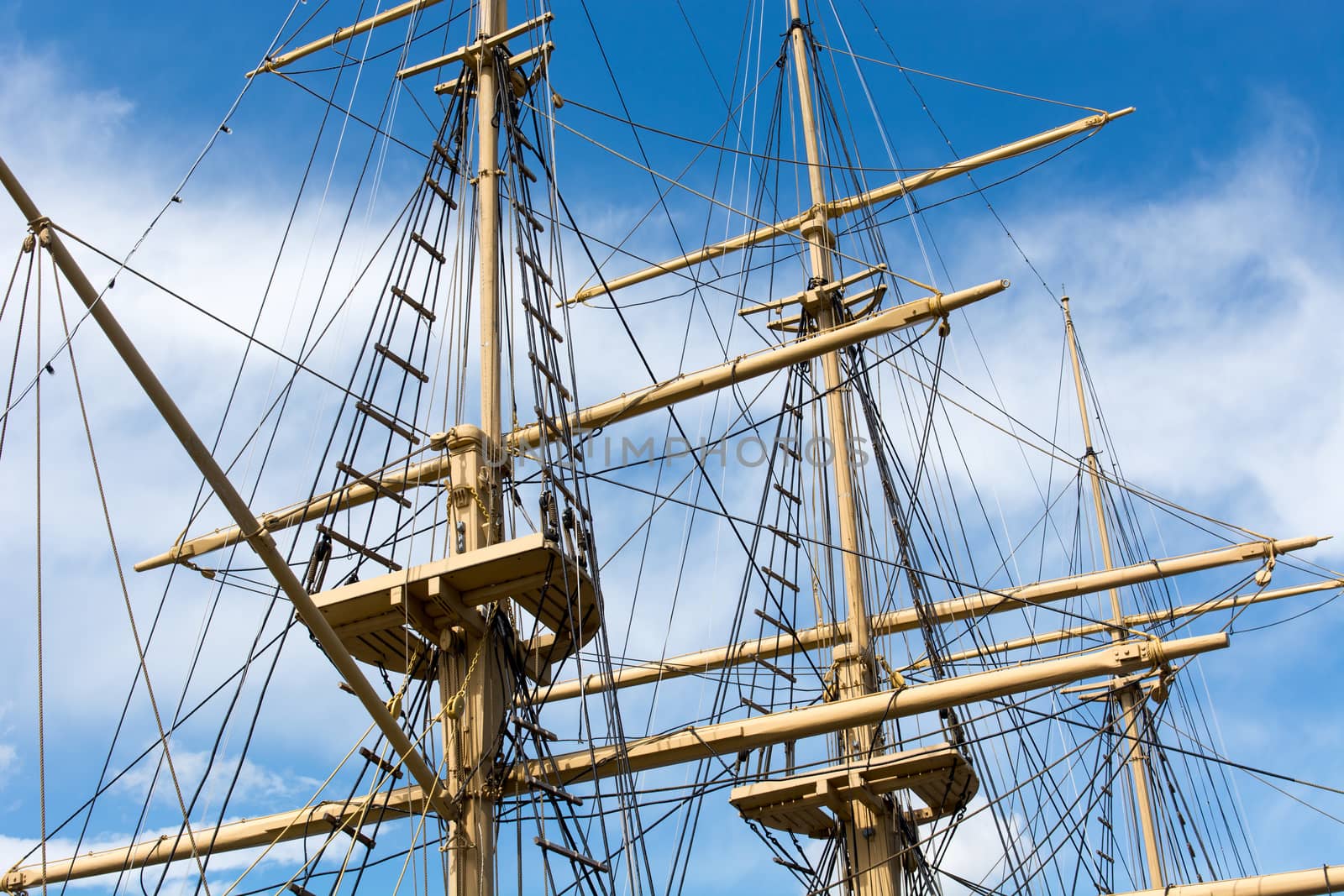 Masts and rigging of a big old sailing ship in front of a blue sky