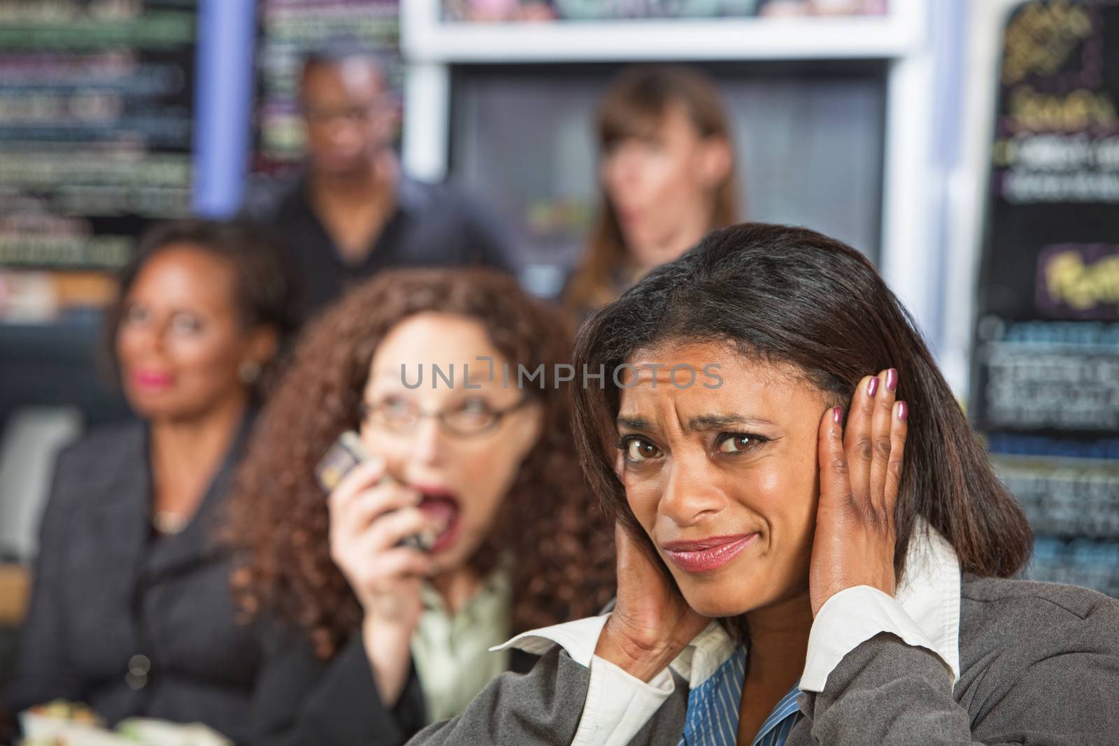 Bothered business person covering ears while person talks