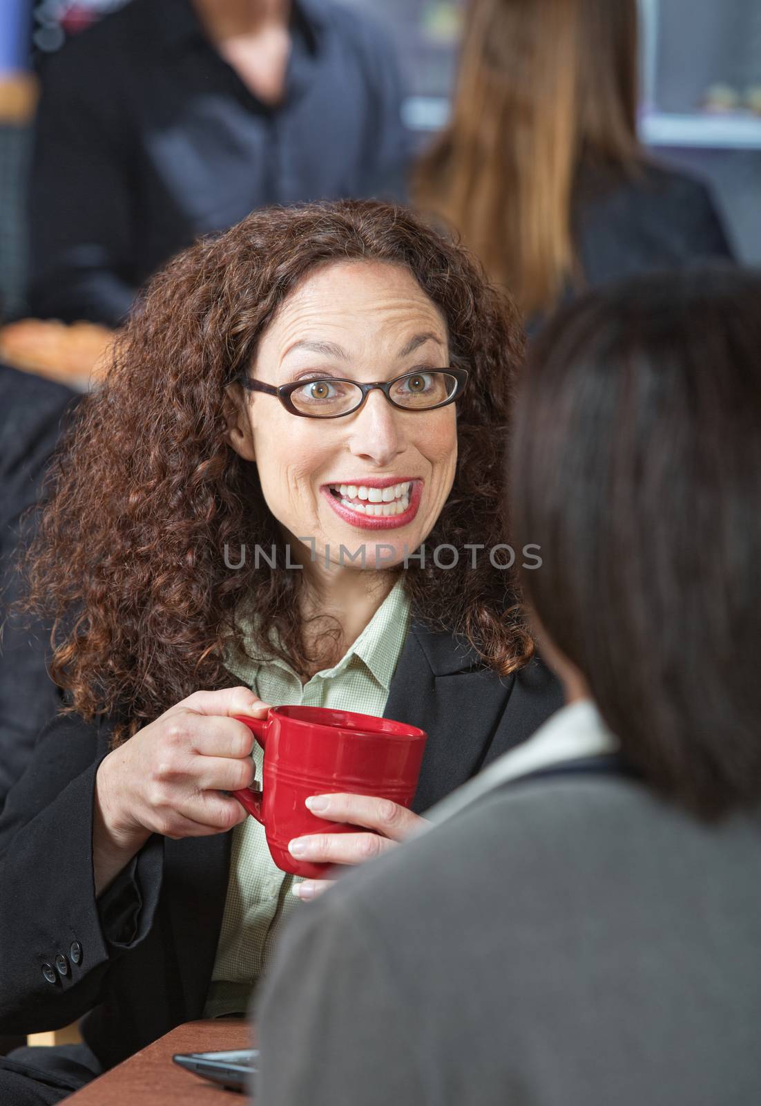 Happy business woman with red mug talking to friend