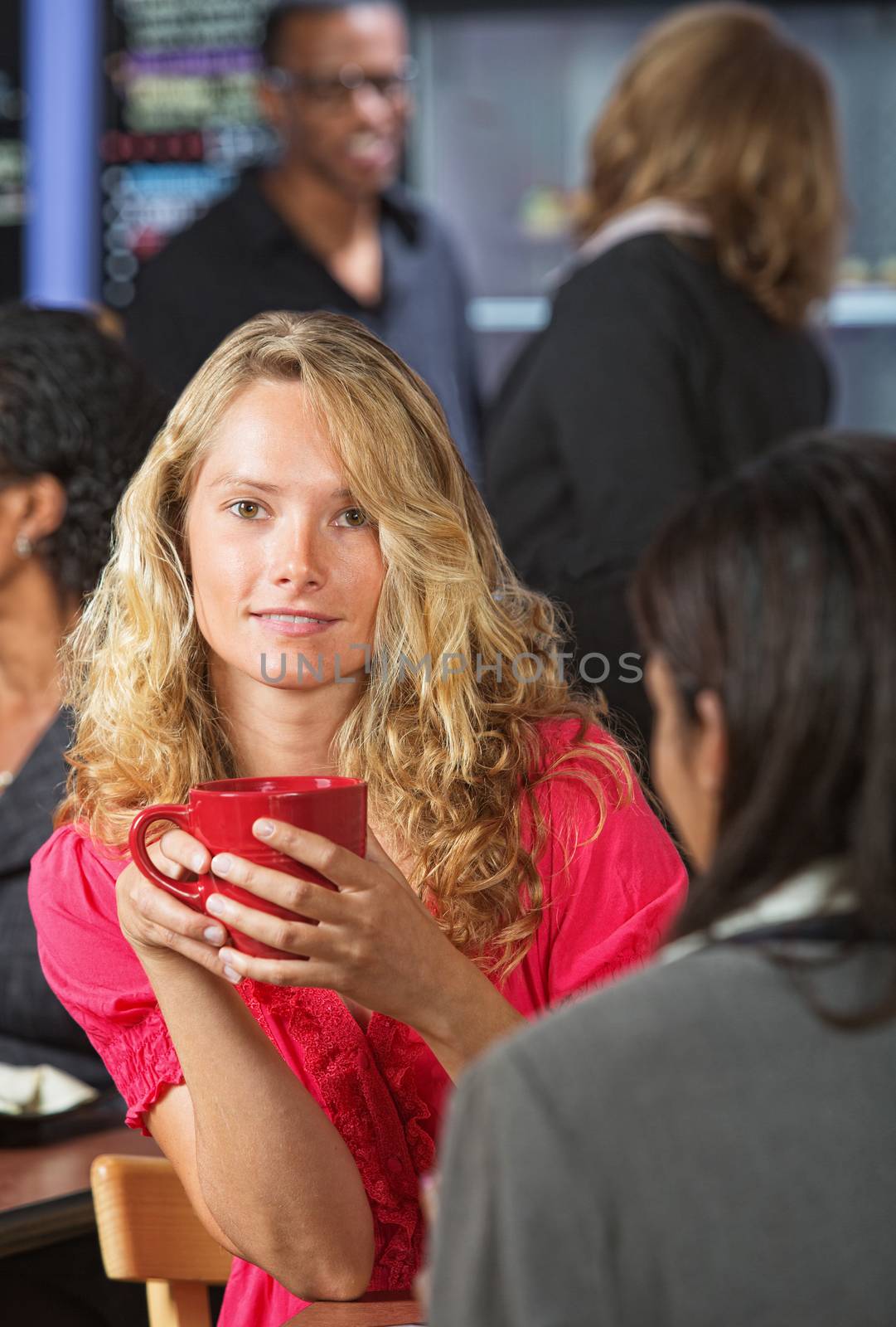 Pretty young woman holding red mug in coffee