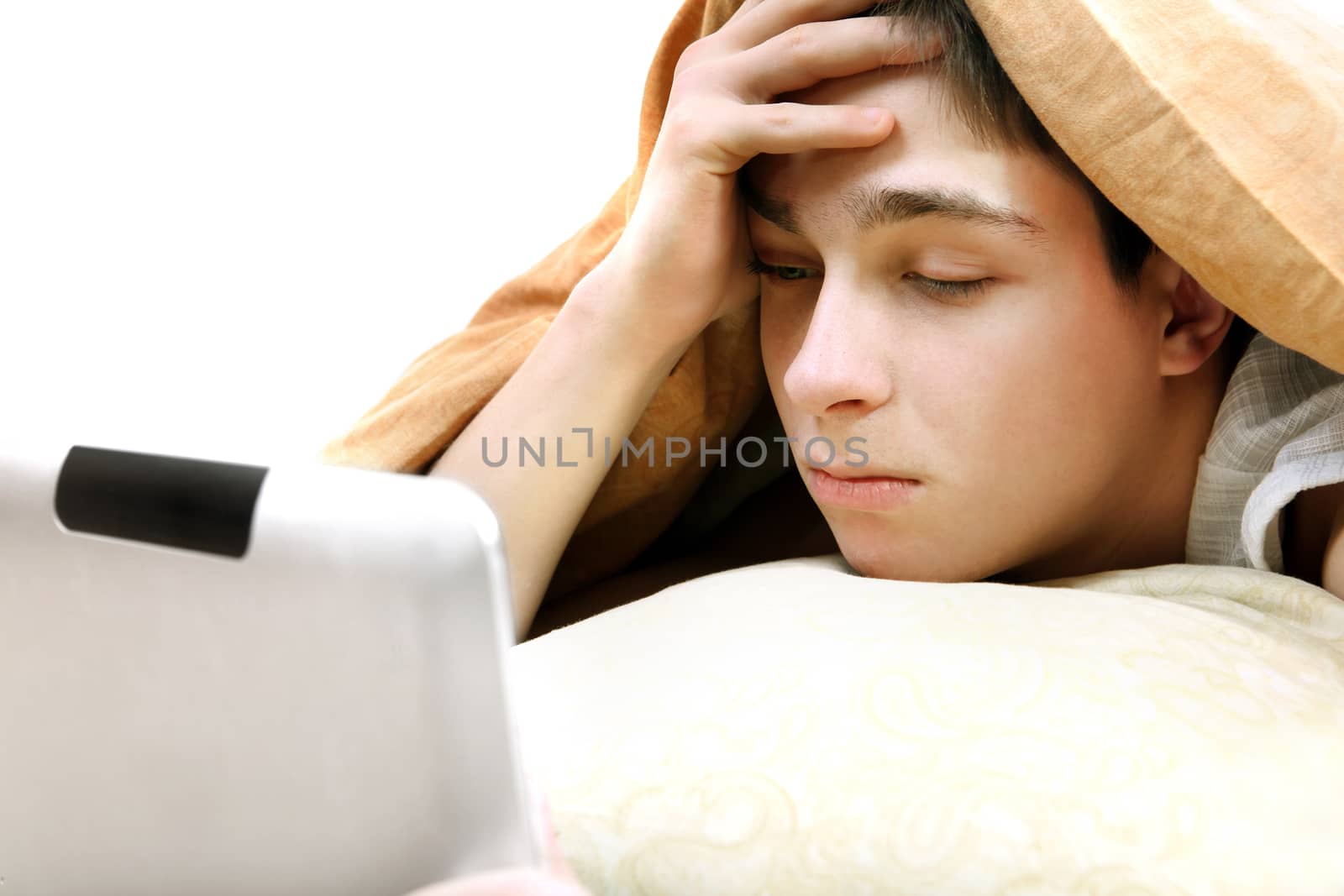 Serious Teenager with Tablet Computer under Blanket at the Home