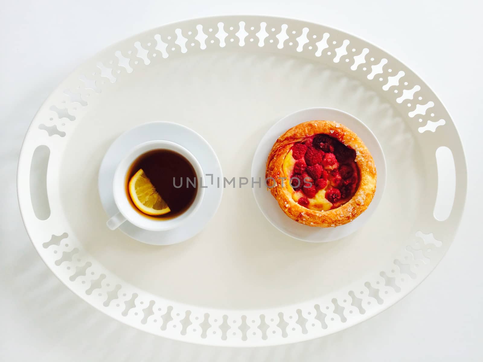 White tray with tasty raspberry pastry and cup of tea.
