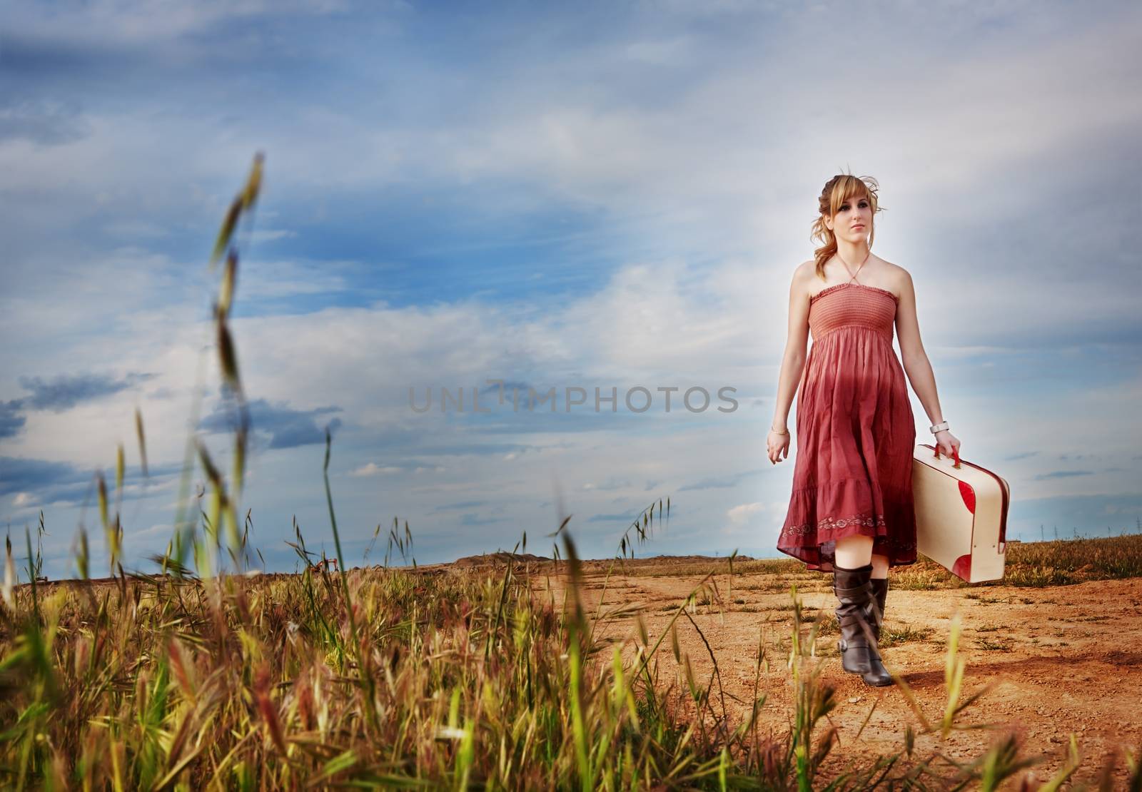 Girl with suitcase walking down a path outdoors. happiness. by Ainat