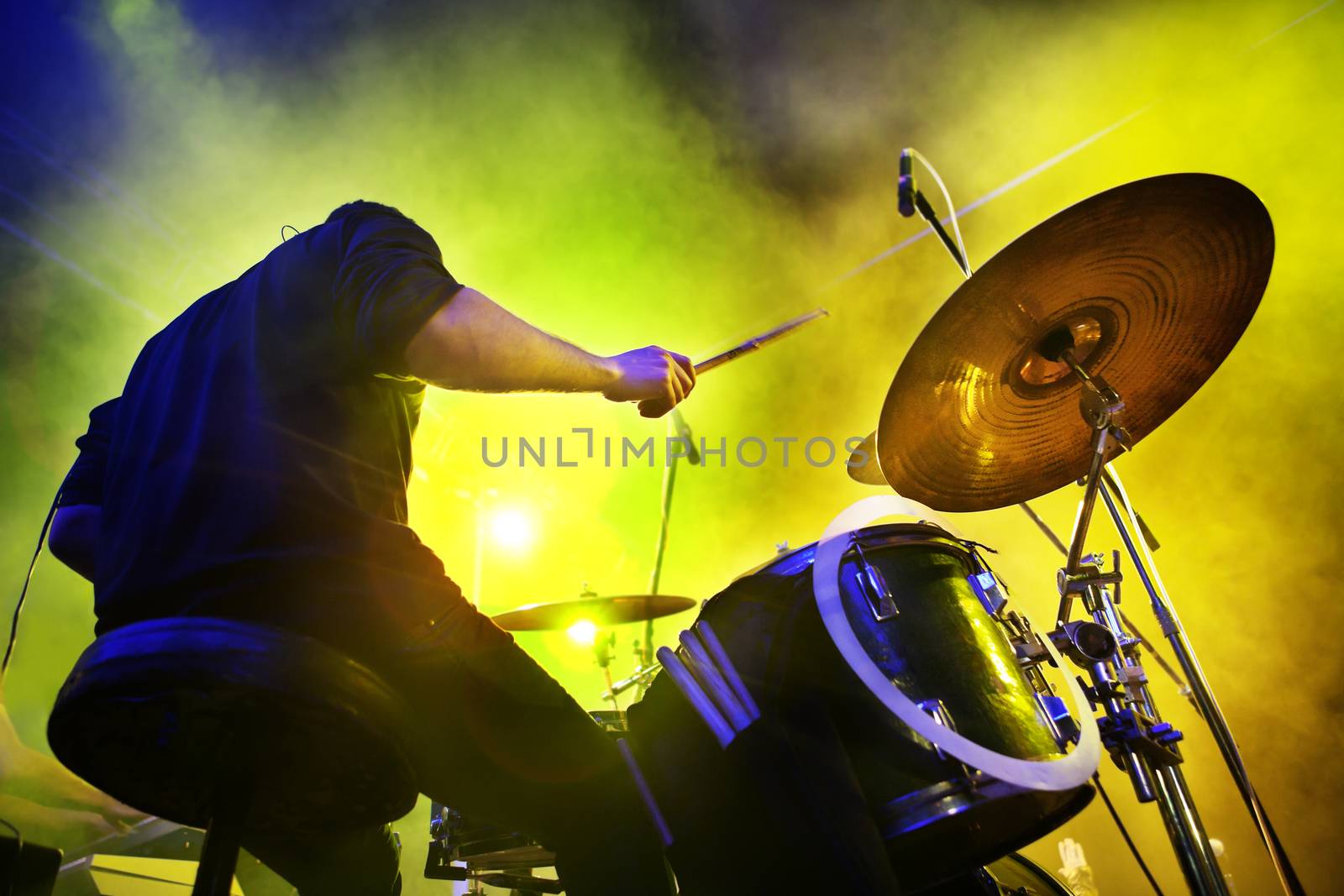 Live concert musician playing drums on stage with lights