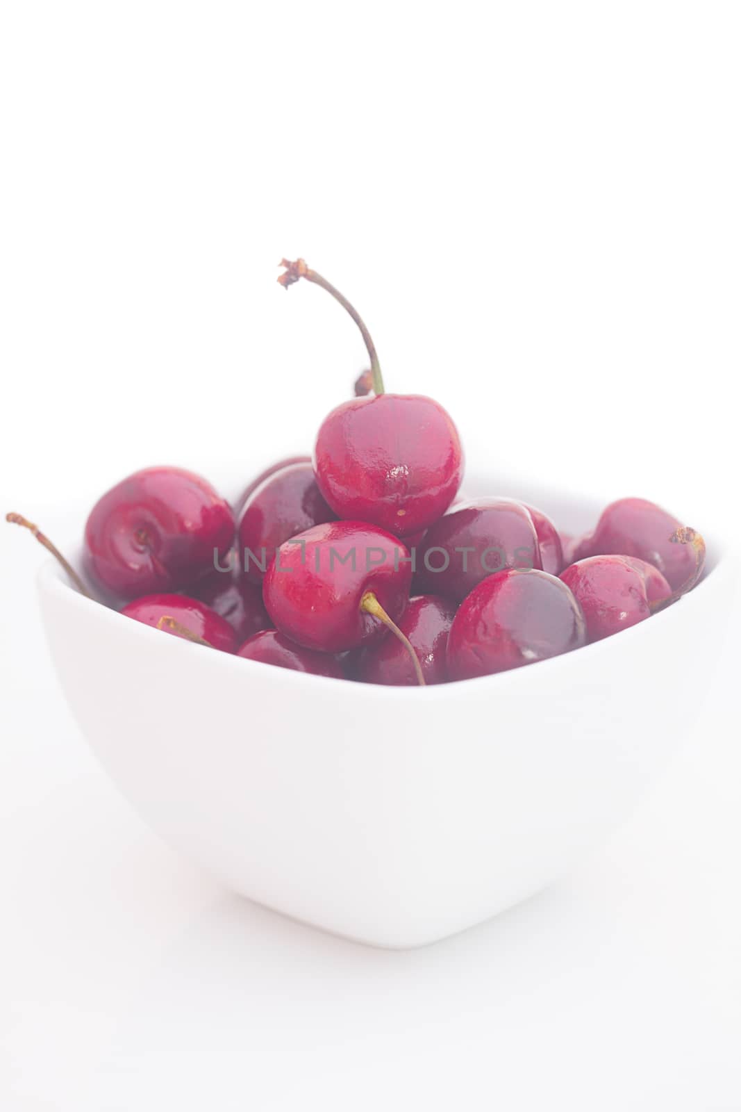 Cherries  in white bowl isolated on white