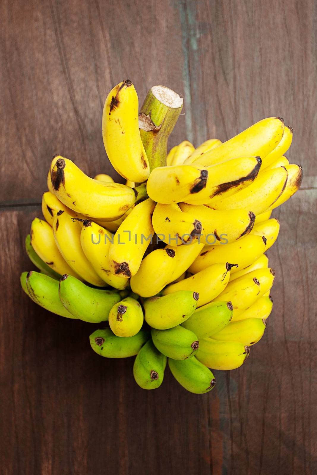 bunch of bananas on a wooden surface by jannyjus