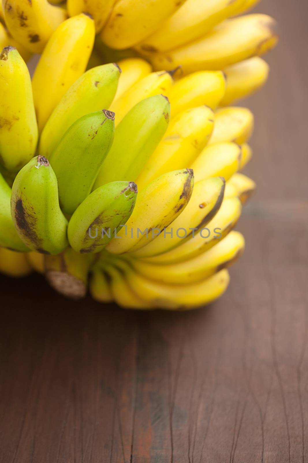 bunch of bananas on a wooden surface by jannyjus