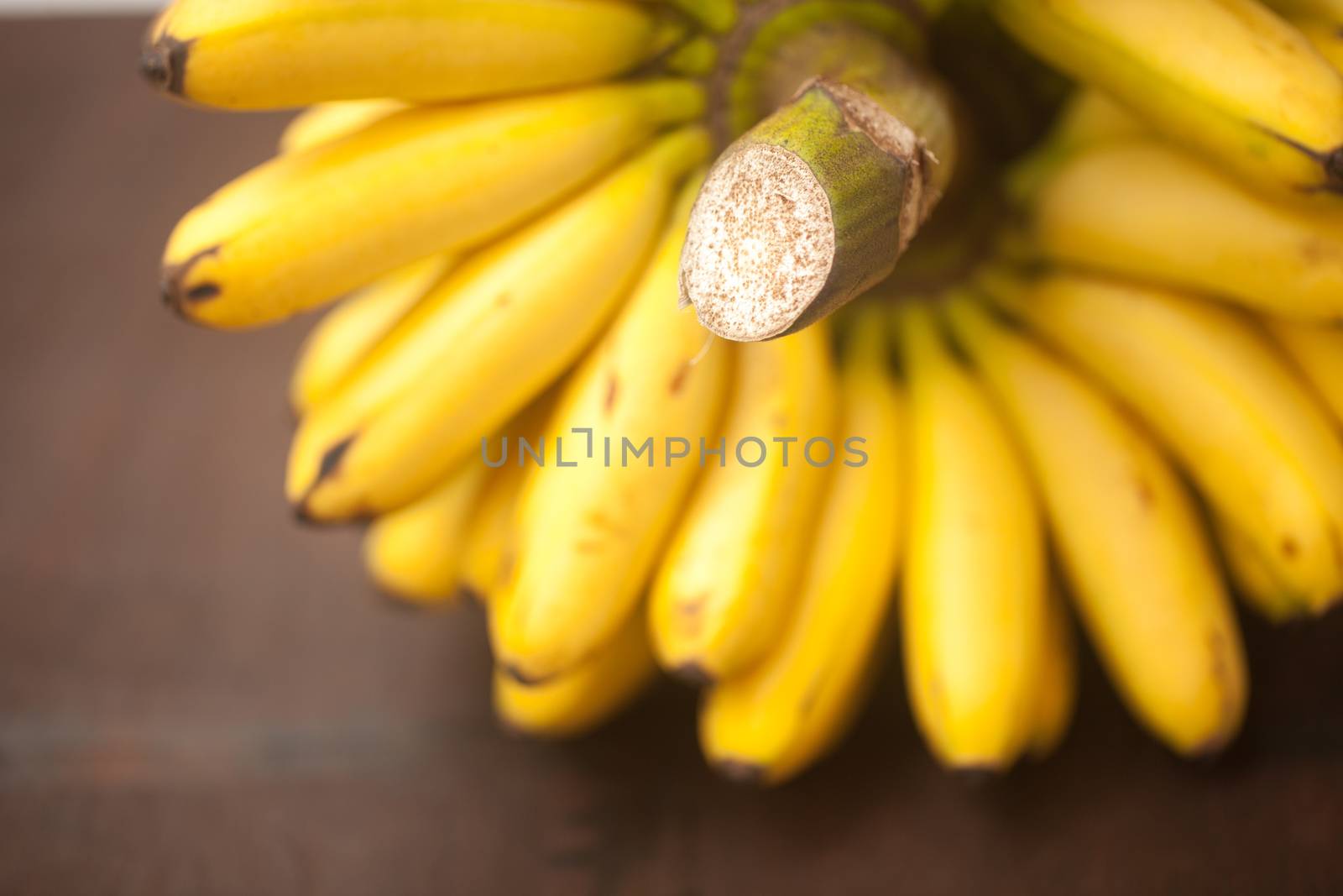 bunch of bananas on a wooden surface by jannyjus