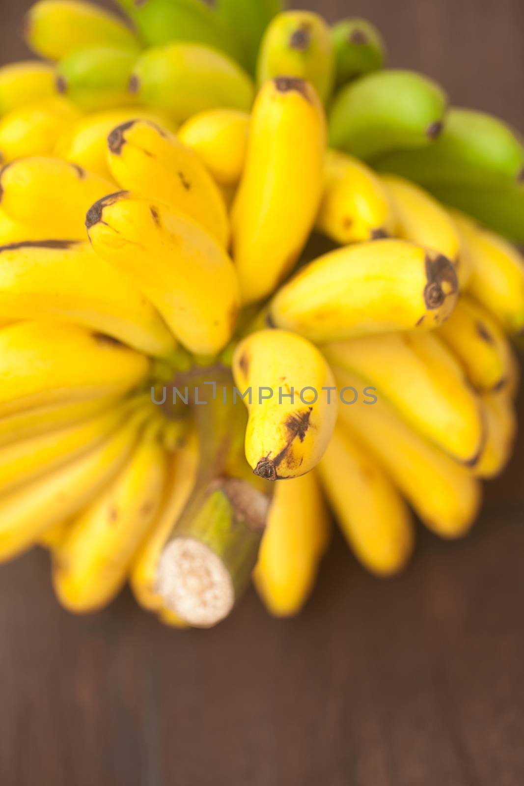 bunch of bananas on a wooden surface by jannyjus