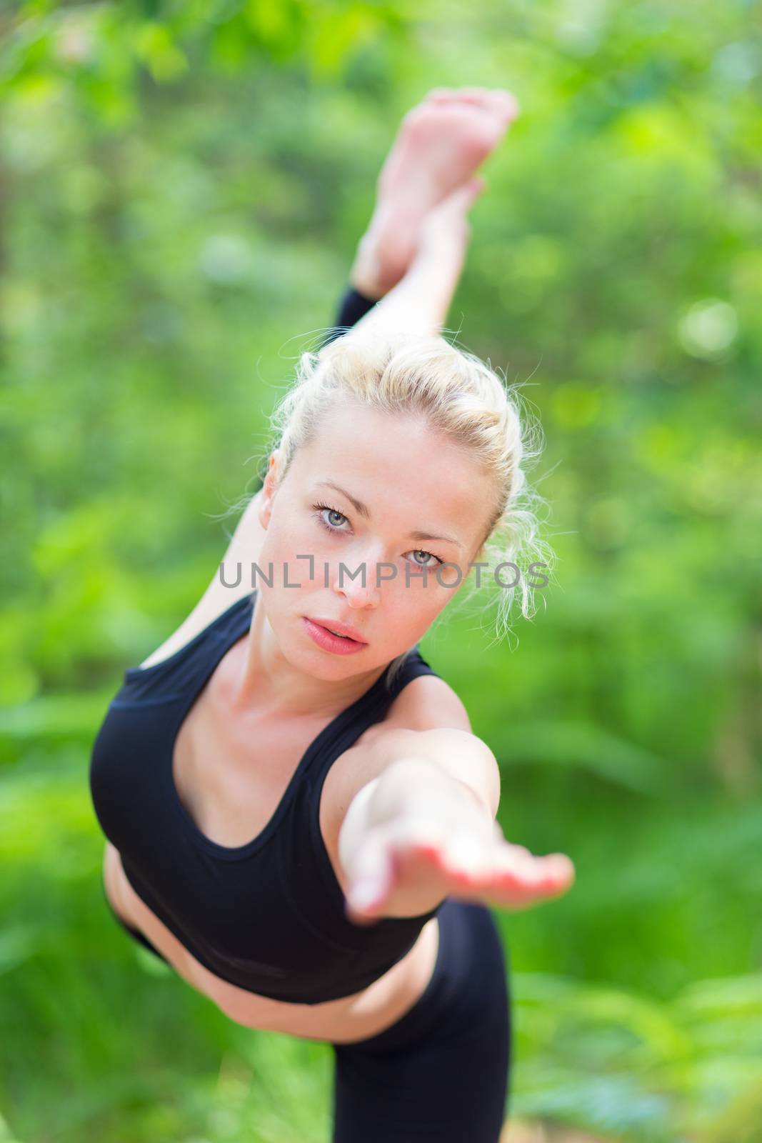 Young caucasian lady is practicing bikram yoga pose in the nature.