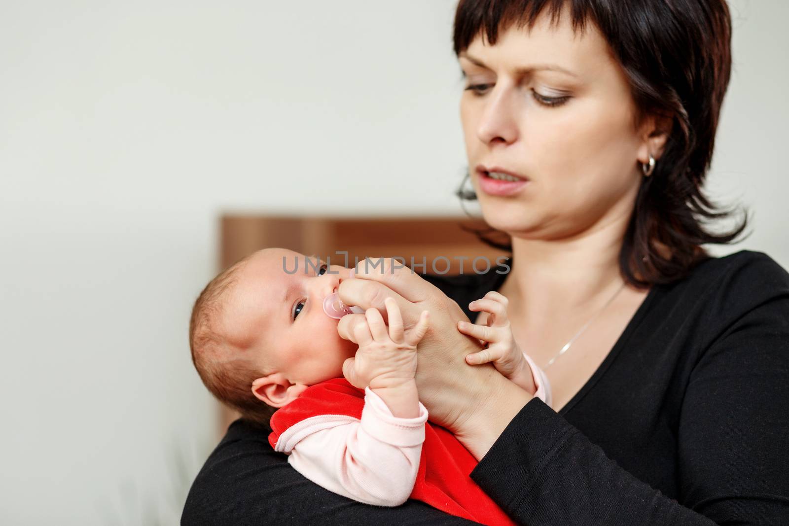 mother with her cute little baby girl, first month of the new life, focus to infant, adjusting pacifier